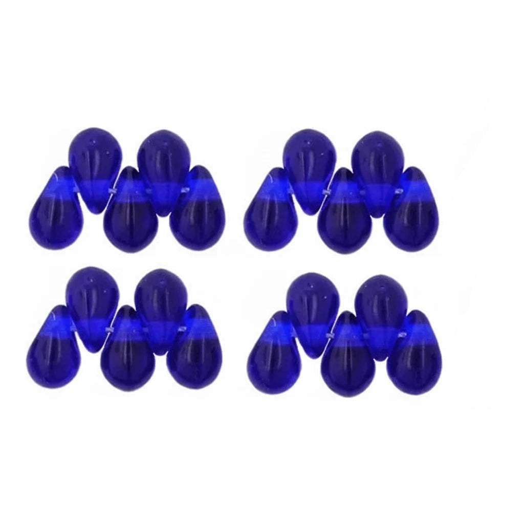 Twelve cobalt blue teardrop-shaped beads arranged in two rows of six on a plain white background.