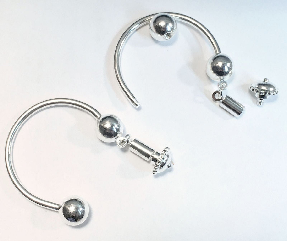 Silver-toned curved hoop earrings with spherical bead details and a small dangling charm, shown on a plain white background.