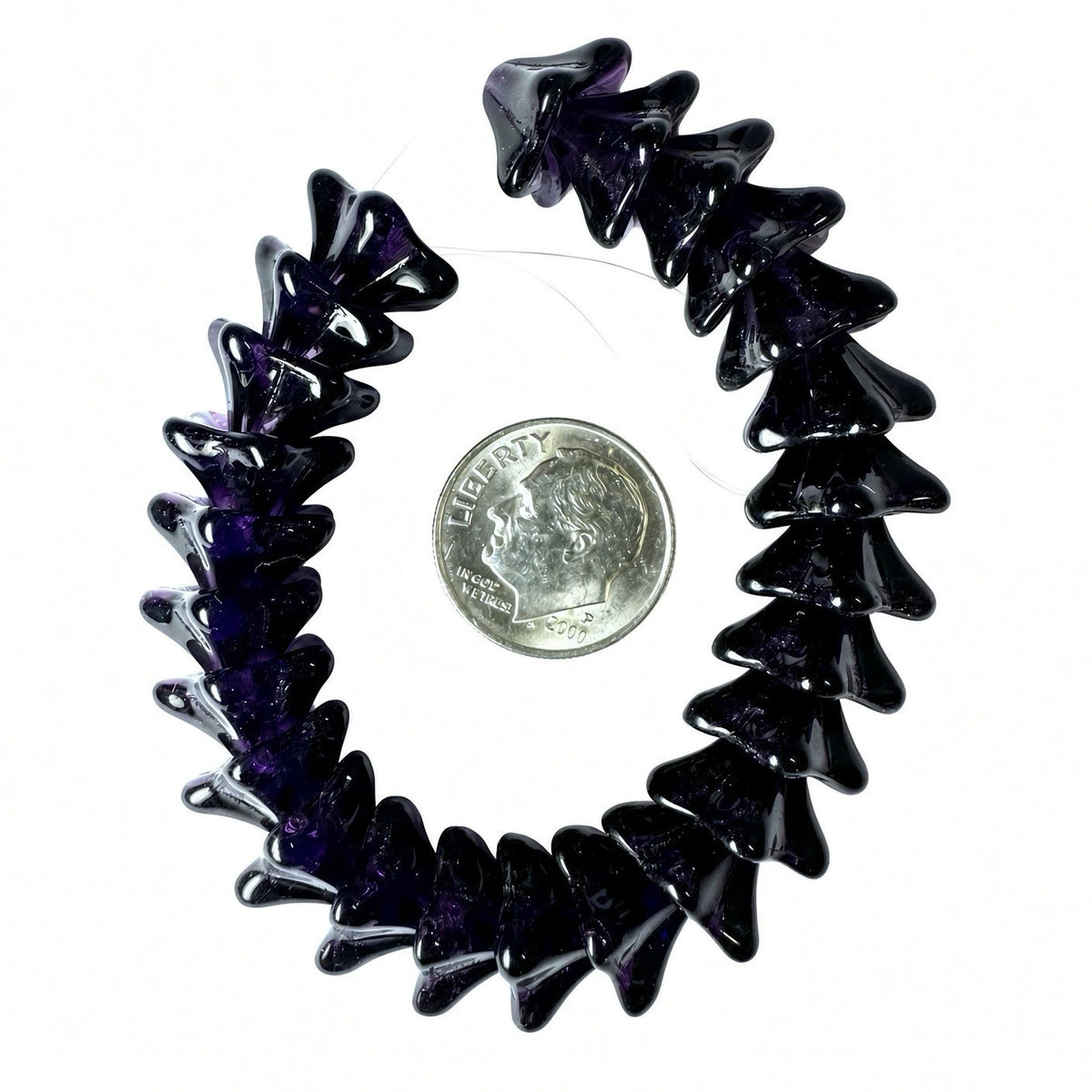 A dark purple and black jagged stone bracelet arranged in a circle next to a US quarter coin for scale, on a white background.