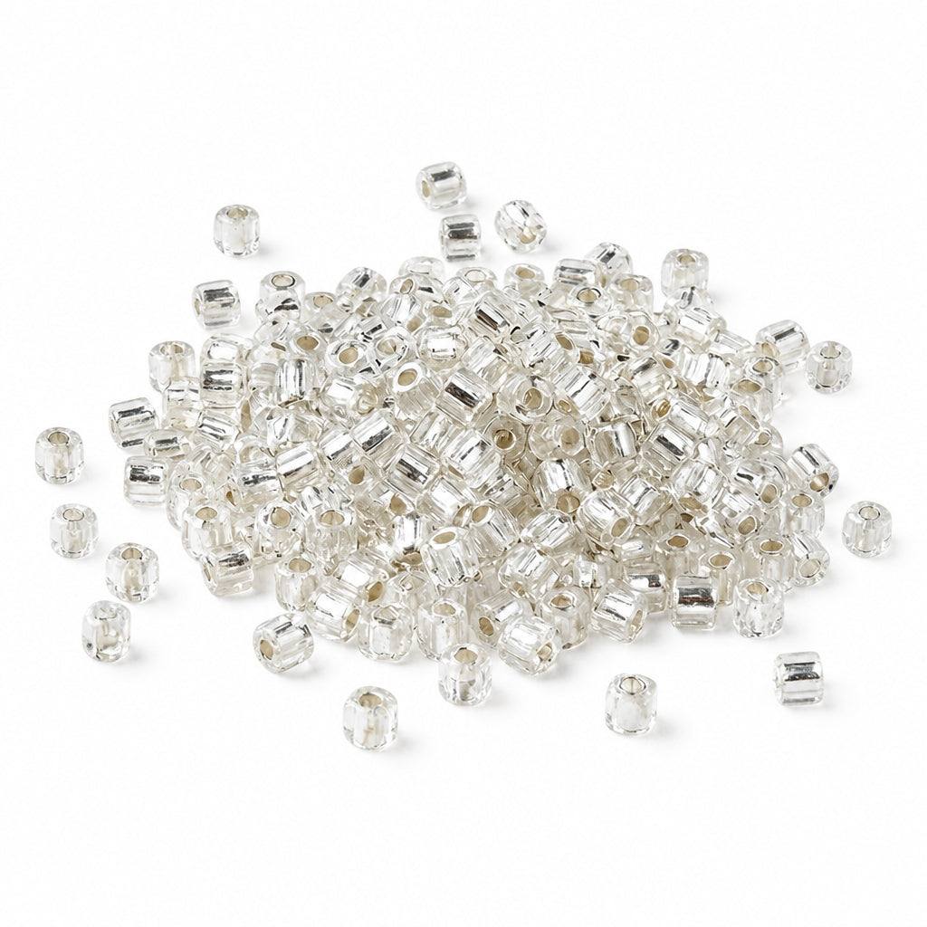 A pile of small clear seed beads with silver-toned metal spacers, scattered on a plain white background.