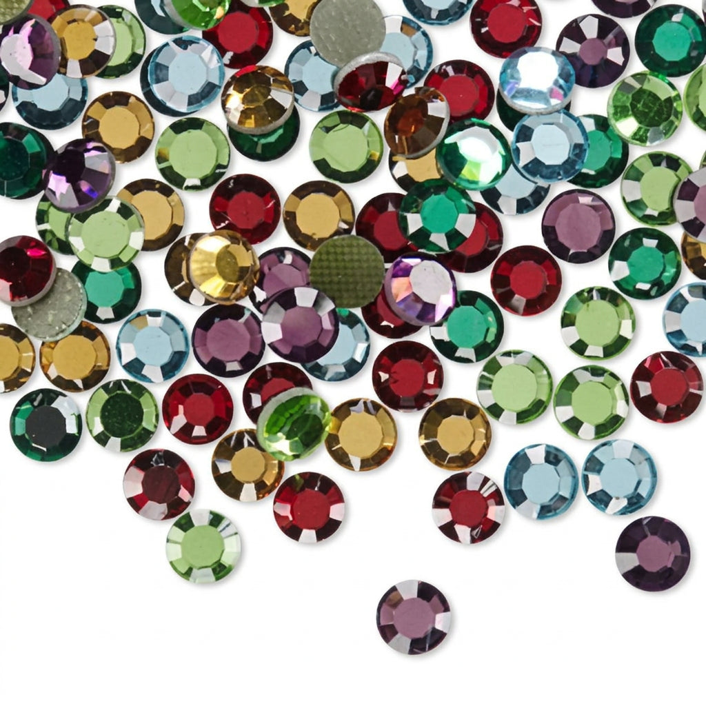 A pile of round, faceted rhinestones in assorted colors, including red, green, blue, gold, and purple, scattered on a plain white background.
