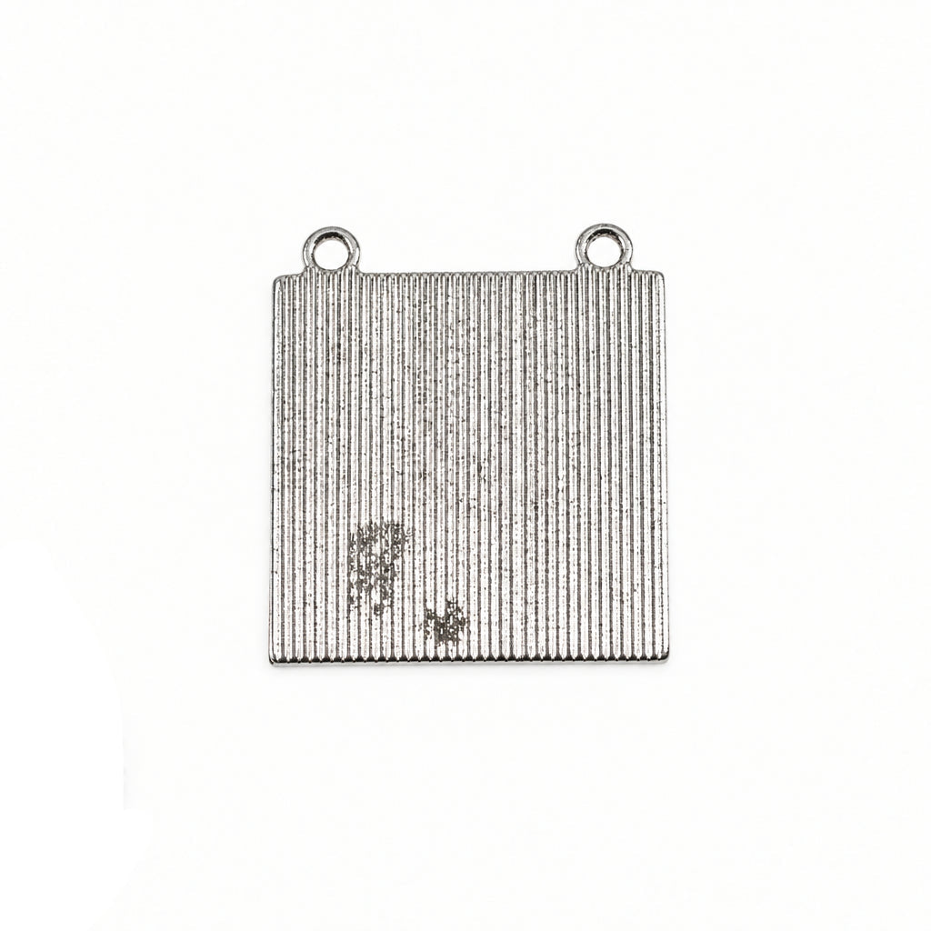 A square silver metal jewelry finding with two loops at the top and a vertically ribbed texture, shown next to a US quarter for scale on a white background.