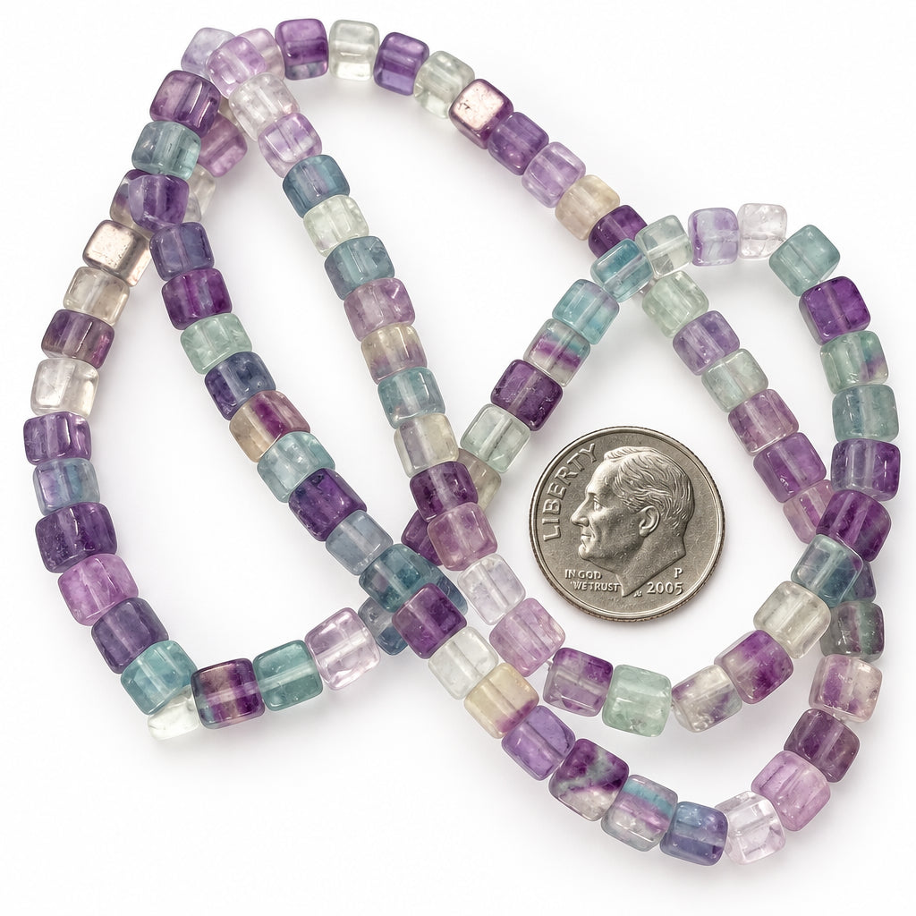 A strand of faceted rectangular beads in pastel lavender, purple, blue, and clear tones, arranged on a white background with a U.S.