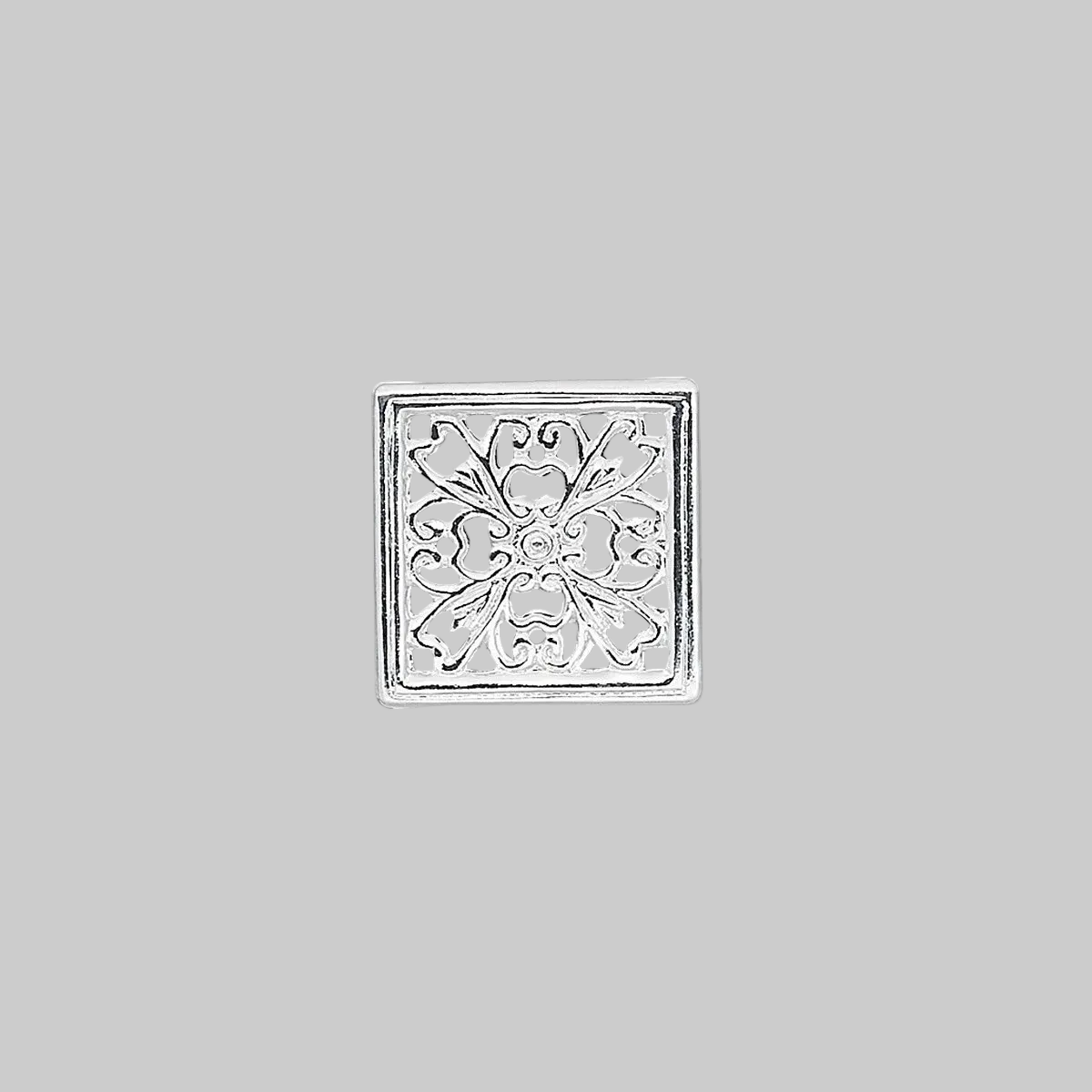 A square silver-toned metal charm with an embossed floral filigree pattern, centered on a solid gray background.