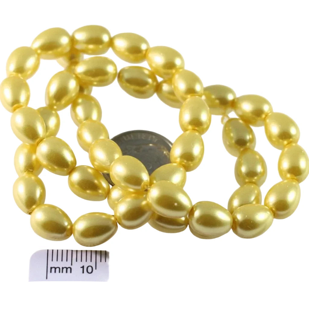 A strand of shiny gold oval beads coiled on a white background, with a US quarter coin and a millimeter ruler included for scale.