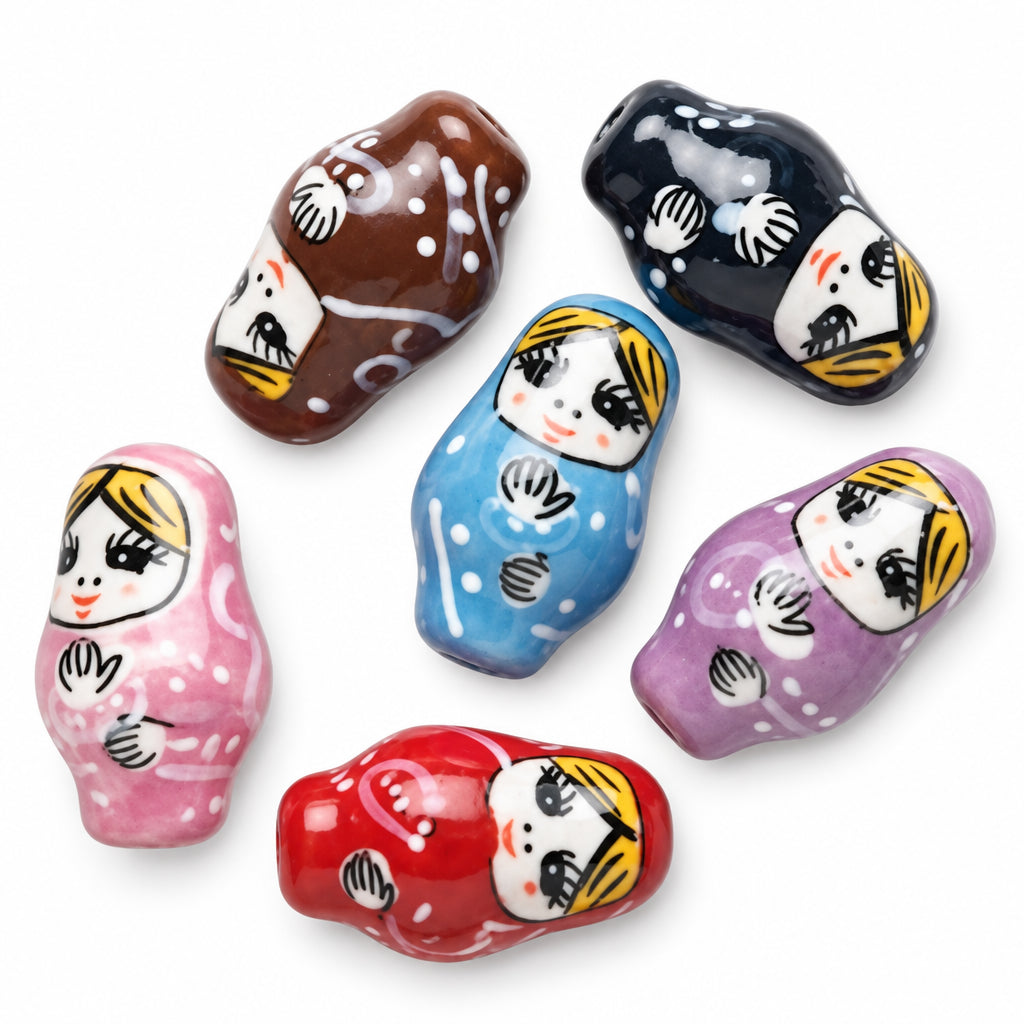 Six hand-painted wooden nesting doll beads in assorted colors including pink, brown, black, blue, purple, and red, arranged on a plain white background.