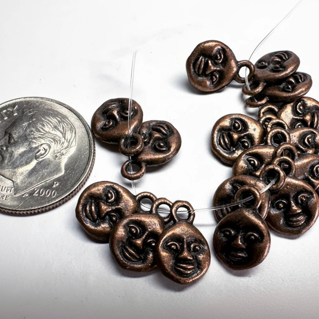 A strand of small bronze-colored metal charms shaped like stylized faces, shown on a white background next to a U.S.