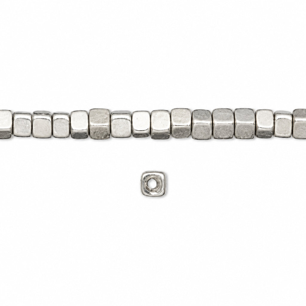 A strand of small metallic silver square beads with a flat, polished finish, shown horizontally on a plain white background with a single loose bead below.
