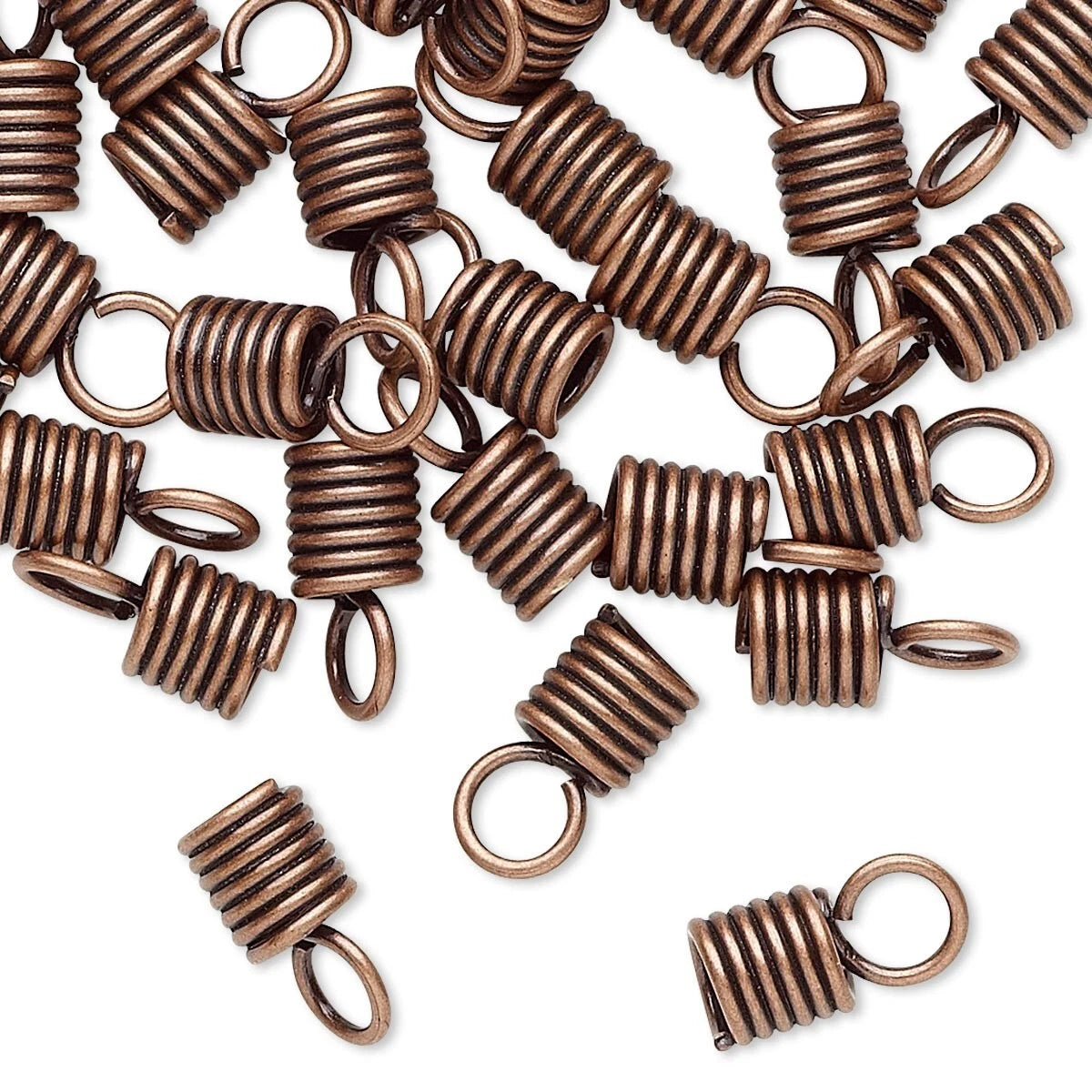 A pile of small spiral spring charms with attached loop ends, shown on a plain white background. The metal has an antique bronze/copper finish.