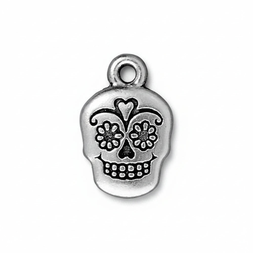 Silver skull charm with floral details on a white background. DAY OF THE DEAD