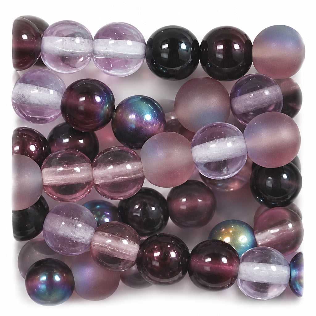Close-up of a strand of round beads in translucent pink, deep purple, and iridescent tones with some glossy black beads.