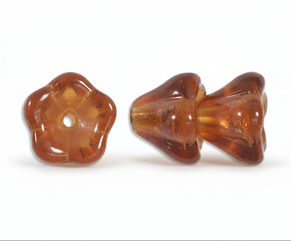 Two amber-brown translucent glass beads, one shaped like a bow and the other like a flower, shown on a plain white background.