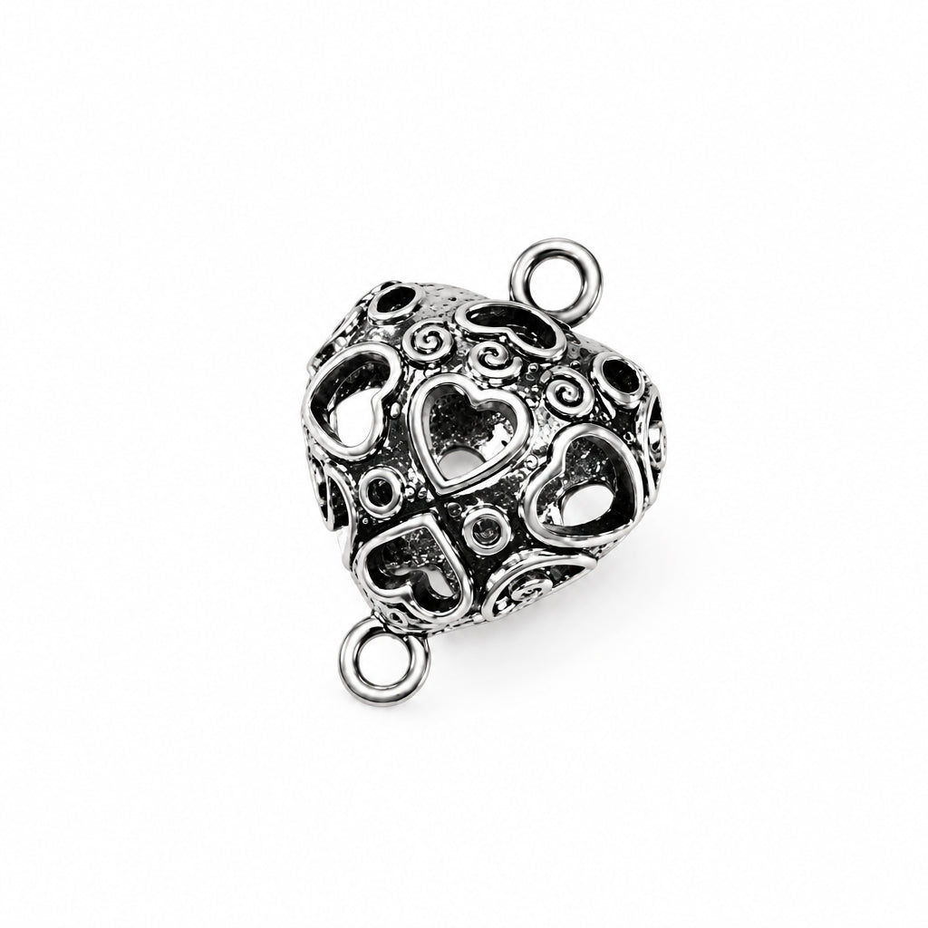 An ornate silver heart-shaped bead charm with intricate cutout patterns and two jump rings, shown on a plain white background.