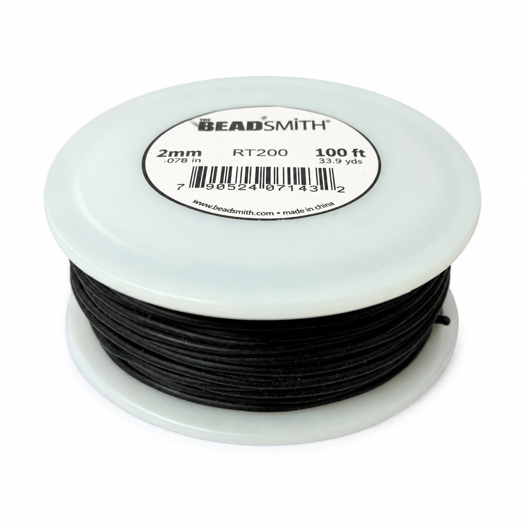 A close-up of a spool of black cord or thread with a white plastic rim and a circular product label on top. The label shows text including '2mm', 'RT200', and '100 ft', along with a barcode and the website beadsmith.