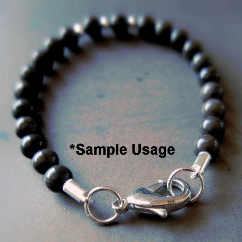 Black beaded bracelet with silver clasp on a gray background
