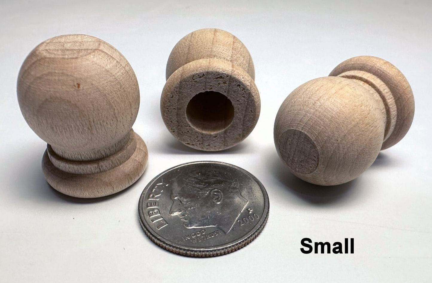 Set of small wooden knobs with a coin for scale on a white background