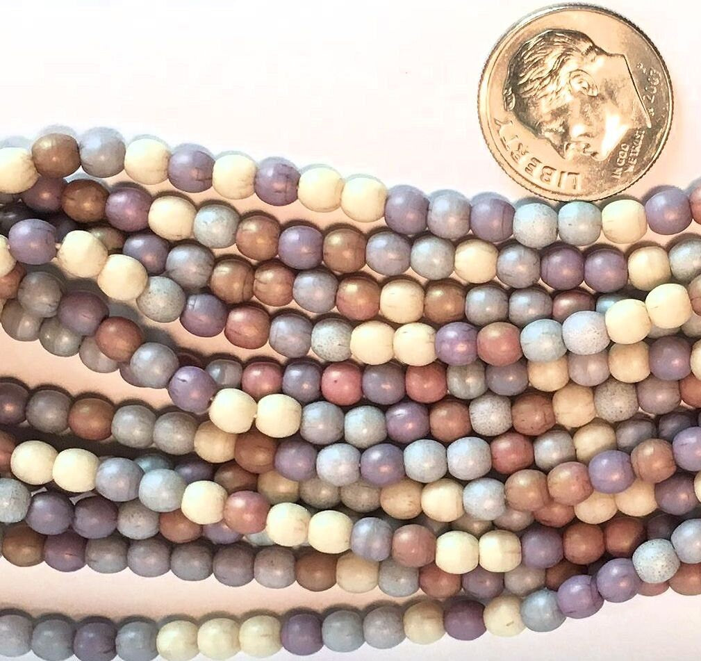 Multicolored beads with a dime for scale on a white background