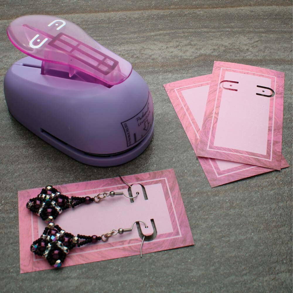 Purple paper punch with pink paper and earrings on a gray surface