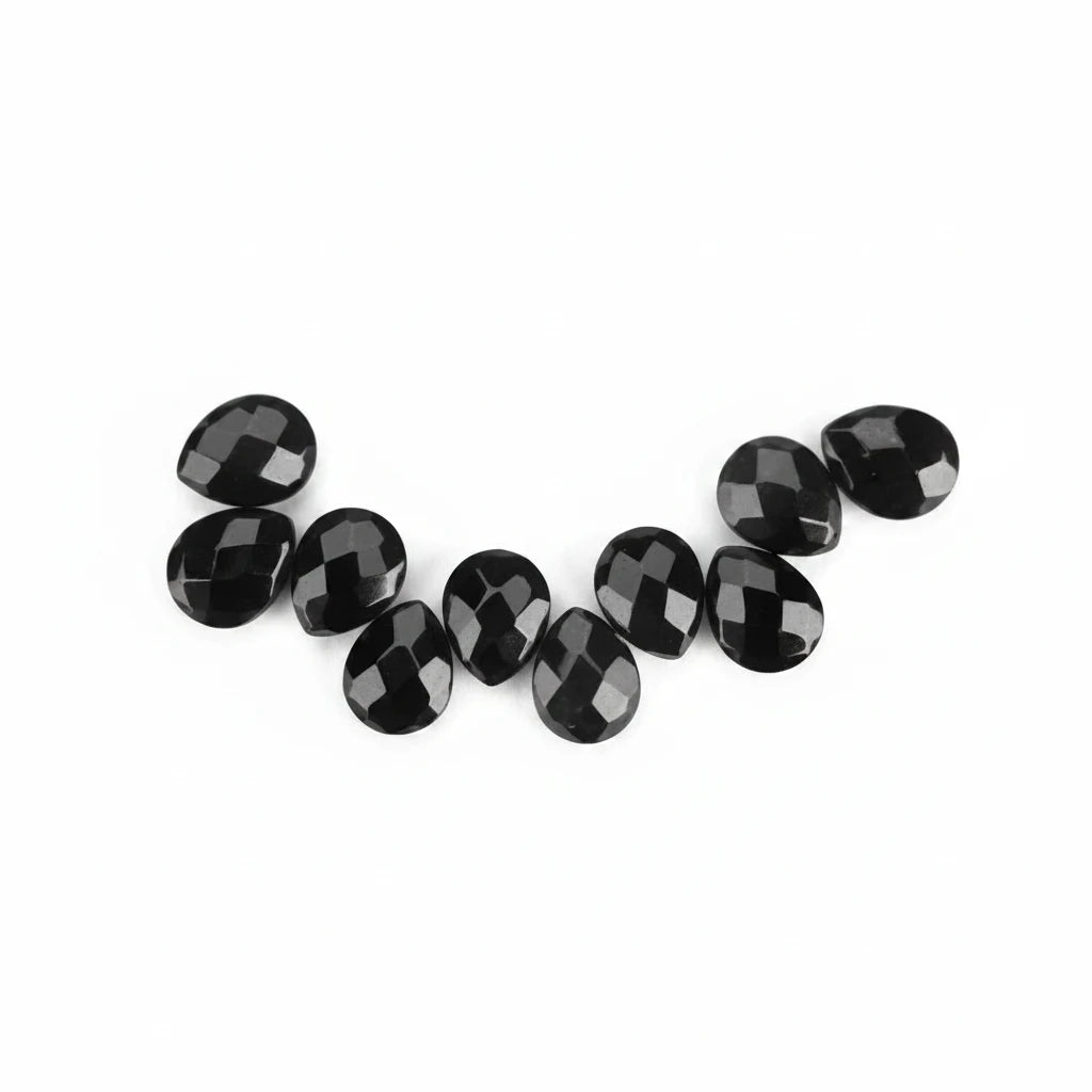 A row of faceted black oval gemstones arranged in a curved line on a plain white background.