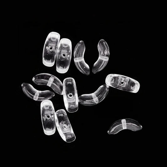 A set of clear, transparent curved plastic beads or spacer pieces scattered on a solid black background, with one piece shown separately in the upper left with a dashed guide line.