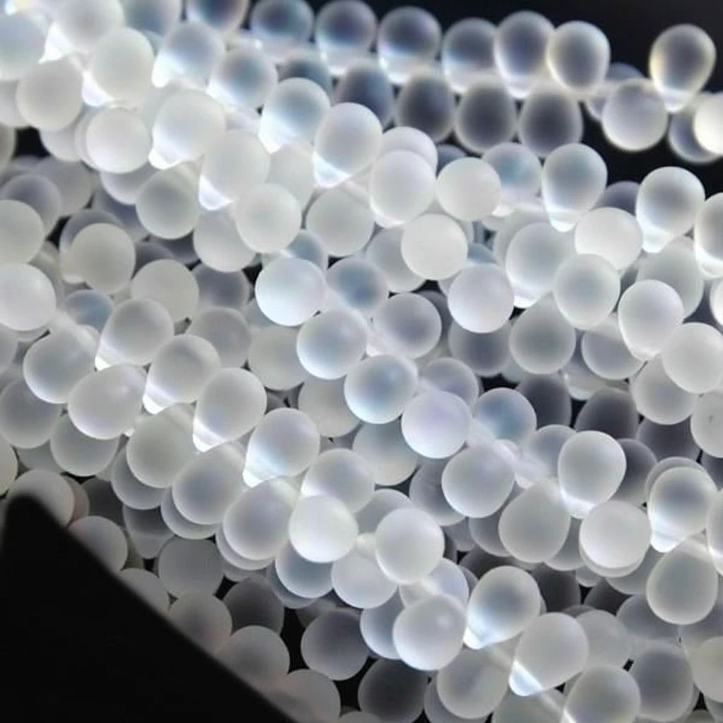 A close-up pile of small, translucent white plastic pellets or beads with a frosted, milky appearance.