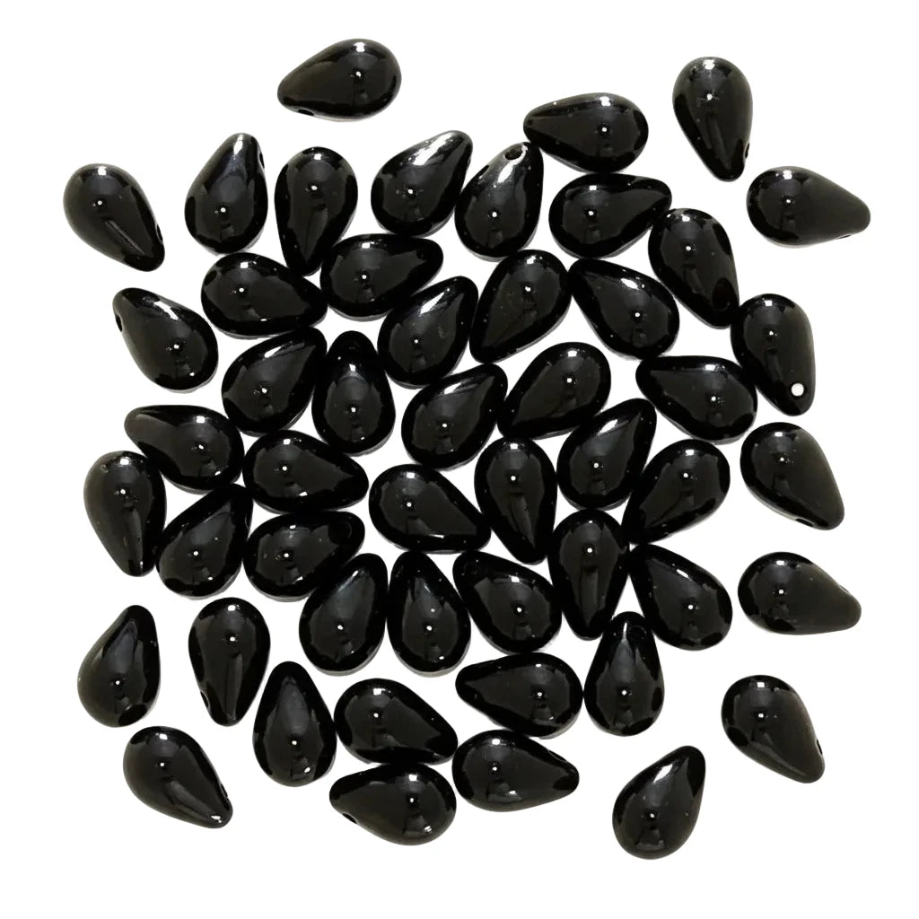 A pile of glossy black teardrop-shaped beads on a plain white background.