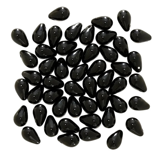A pile of glossy black teardrop-shaped beads on a plain white background.