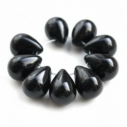 A bracelet made of glossy black teardrop-shaped beads strung on a thin silver wire, shown against a plain white background.