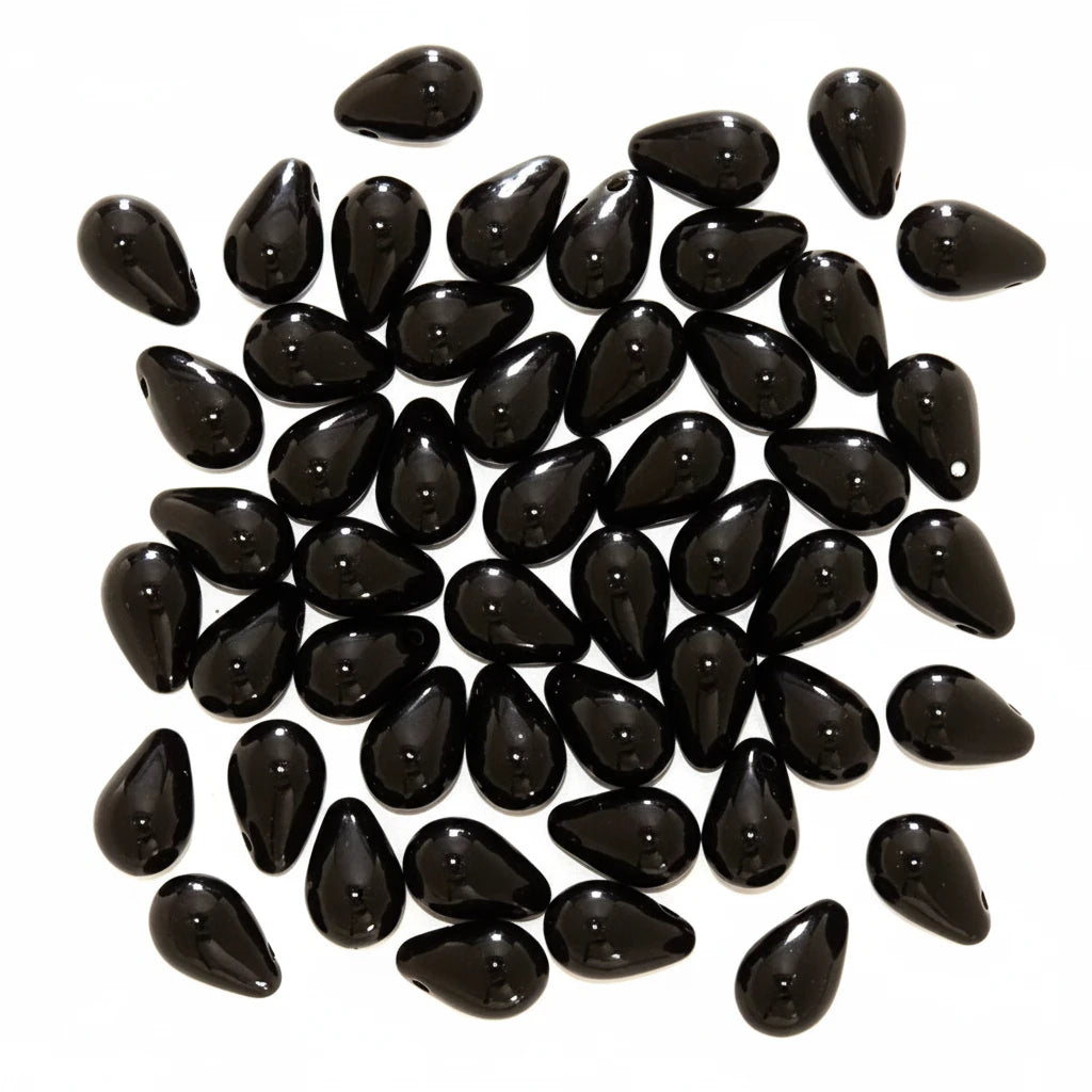 A pile of glossy black teardrop-shaped beads on a plain white background.