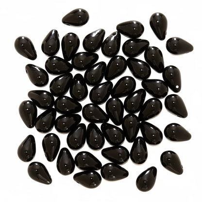 A pile of glossy black teardrop-shaped beads on a plain white background.