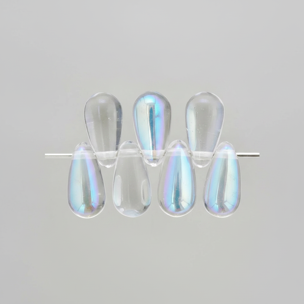 Six clear teardrop-shaped cabochon beads with an iridescent blue and purple sheen, arranged on a thin metal rod against a light gray background.