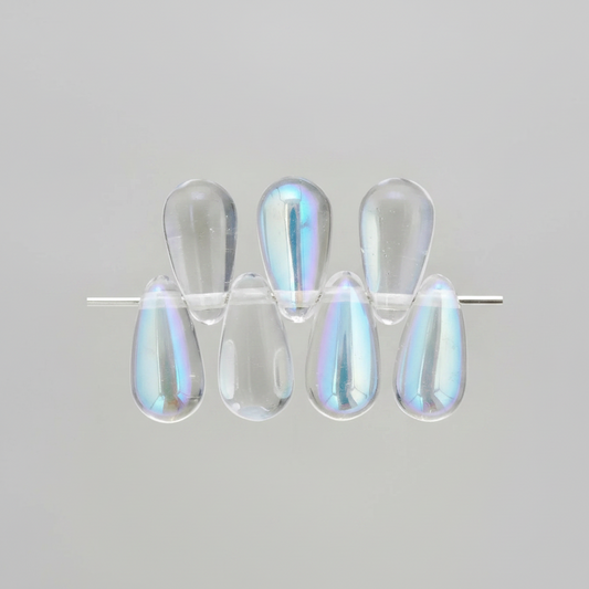Six clear teardrop-shaped cabochon beads with an iridescent blue and purple sheen, arranged on a thin metal rod against a light gray background.