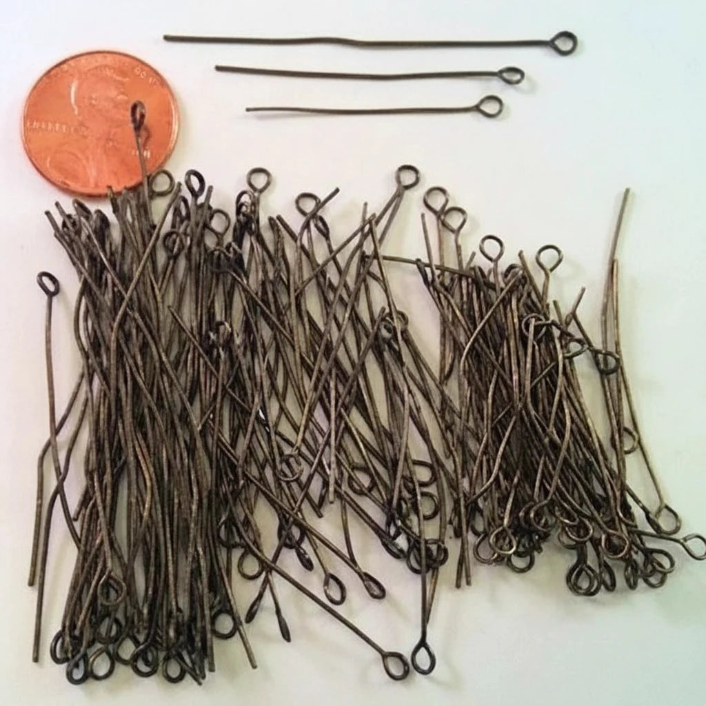 A pile of dark metal loop pins with looped ends, shown with three longer matching pins and a copper penny for scale on a white background. The text 'The Mystical Garden Path' is visible at the bottom.