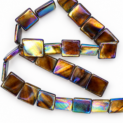 Square iridescent glass beads with a metallic gold, bronze, and rainbow holographic finish, arranged in loops on a white background.