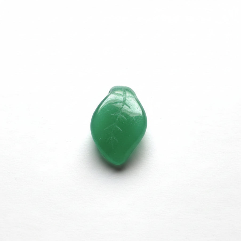 Green translucent stone beads with a leaf vein pattern, arranged on a white surface.