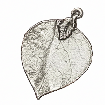 A leaf-shaped pendant or charm with a textured, metallic silver appearance and a small loop at the top. The word 'Mystical Garden Pa' is printed across the center on a plain white background.