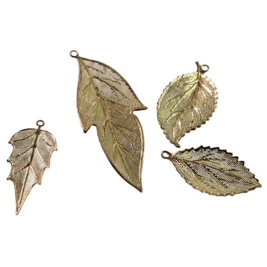 Four gold-toned metal leaf-shaped charms with textured mesh details and small hanging loops, arranged on a plain white background.