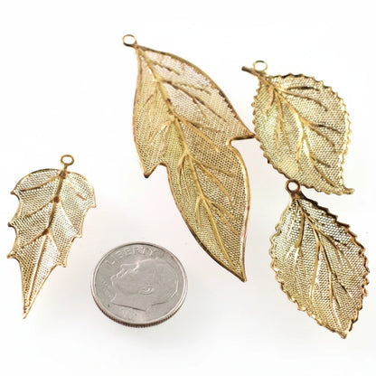 Four gold-toned leaf-shaped metal charms with a textured mesh pattern and small hanging loops, displayed on a white background with a U.S.