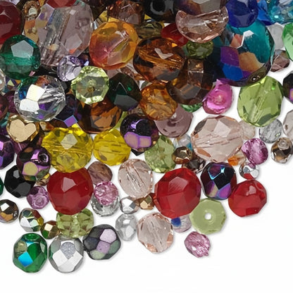 A pile of assorted faceted rhinestones and craft gems in multiple colors, including red, green, pink, yellow, blue, purple, and clear, arranged on a white background.