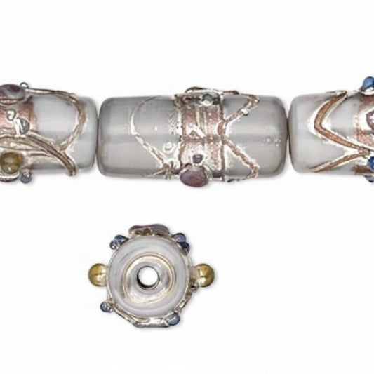 A close-up of decorative glass beads on a white background, showing a cylindrical bead with silver-toned wire wrapping and a separate top-down view of the bead's end with small gold and blue accents.