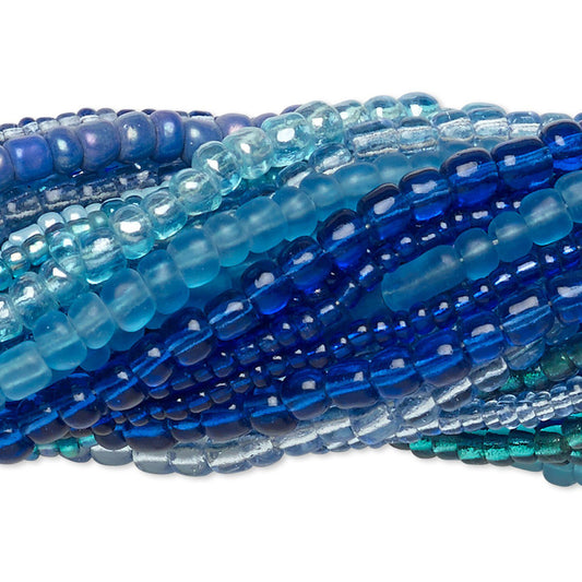 Multiple strands of faceted glass beads in shades of blue, teal, and aqua, arranged in overlapping layers on a white background.