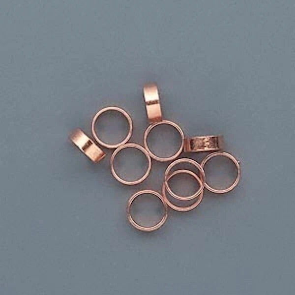 copper metal ring spacers with loop tops, arranged on a solid slate blue background.