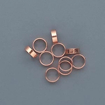 copper metal ring spacers with loop tops, arranged on a solid slate blue background.