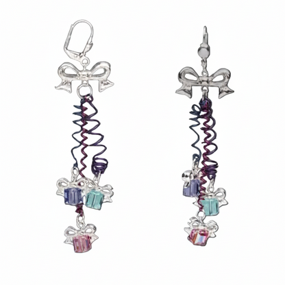 A pair of dangling earrings shown on a plain gray background, with one earring displayed normally and a smaller inset view showing the back hook detail. The earrings have silver-toned bow charms, spiral purple and blue wire strands, and dangling gift box charms in blue, aqua, and pink.