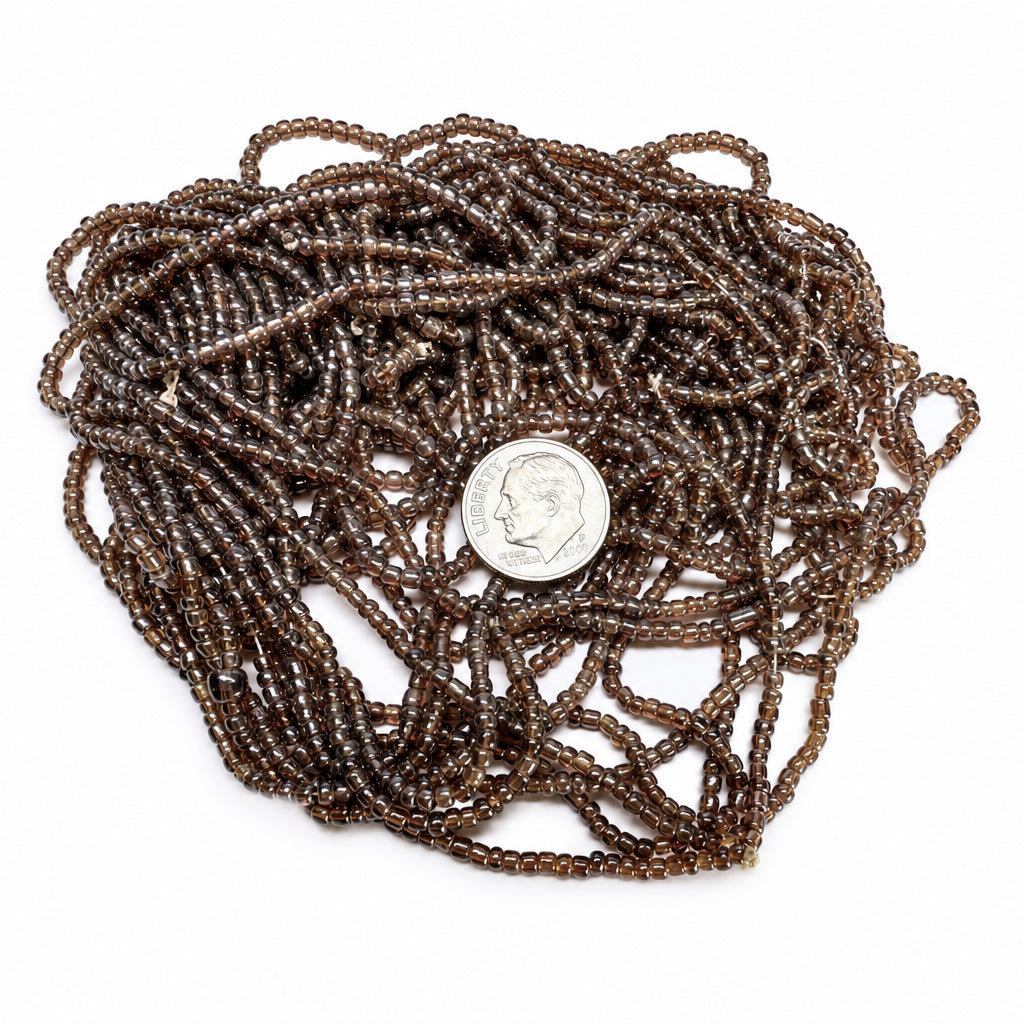 A coiled bundle of dark brown translucent glass seed beads with a silver-colored US dime placed in the center for scale, on a plain white background.