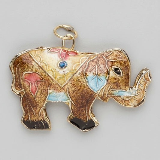 An ornate elephant-shaped pendant or charm with a gold-tone outline and loop at the top, decorated with multicolored enamel in brown, gold, pink, blue, and black on a plain gray background.