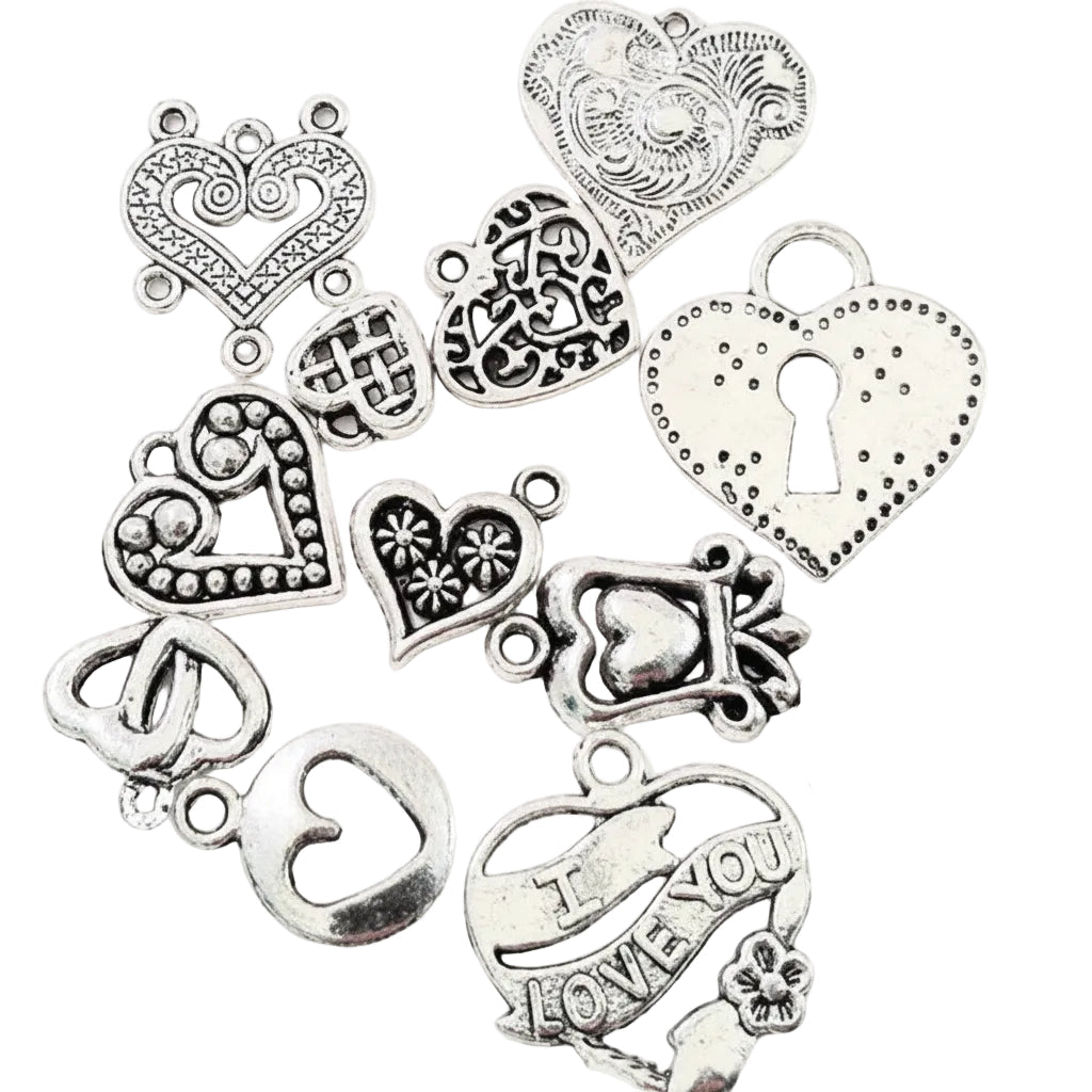 A set of antique silver heart-shaped charms with various engravings, dots, keyhole details, and one charm reading 'I LOVE YOU,' arranged on a white background next to a US quarter for scale.