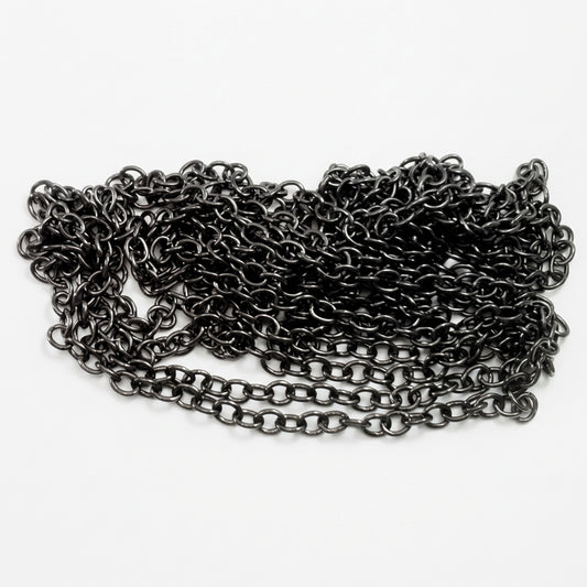 A coiled length of dark metallic chain links, shown on a white background with a US quarter coin for scale.