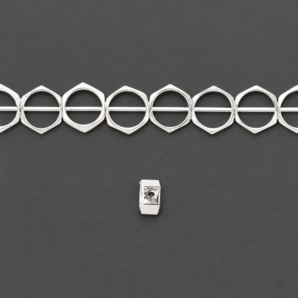A strand of silver-toned metal spacer rings, likely for jewelry making, shown against a solid dark gray background with a small white rectangular label below.