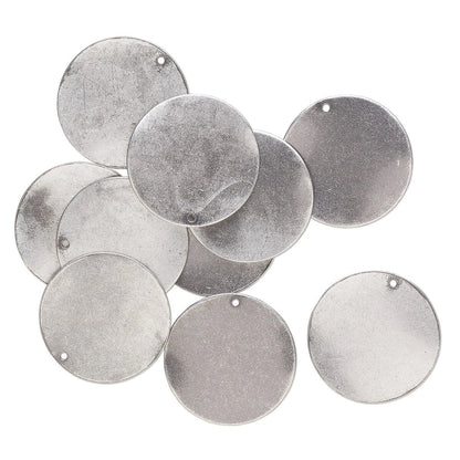 A pile of round silver metal nameplates or tags with small pre-drilled holes, displayed on a clean white background.